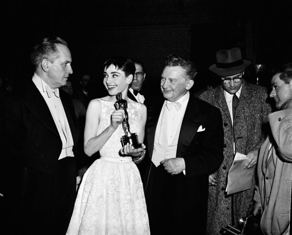 26TH ANNUAL ACADEMY AWARDS -- New York Ceremony -- Air Date 03/25/1954 -- Pictured: Host/actor Fredric March, Best Actress winner Audrey Hepburn for "Roman Holiday", actor Jean Hersholt during the 26th Annual Academy Awards on March 25, 1954 held at the NBC Century Theatre in New York City (Photo by NBC/NBCU Photo Bank via Getty Images)