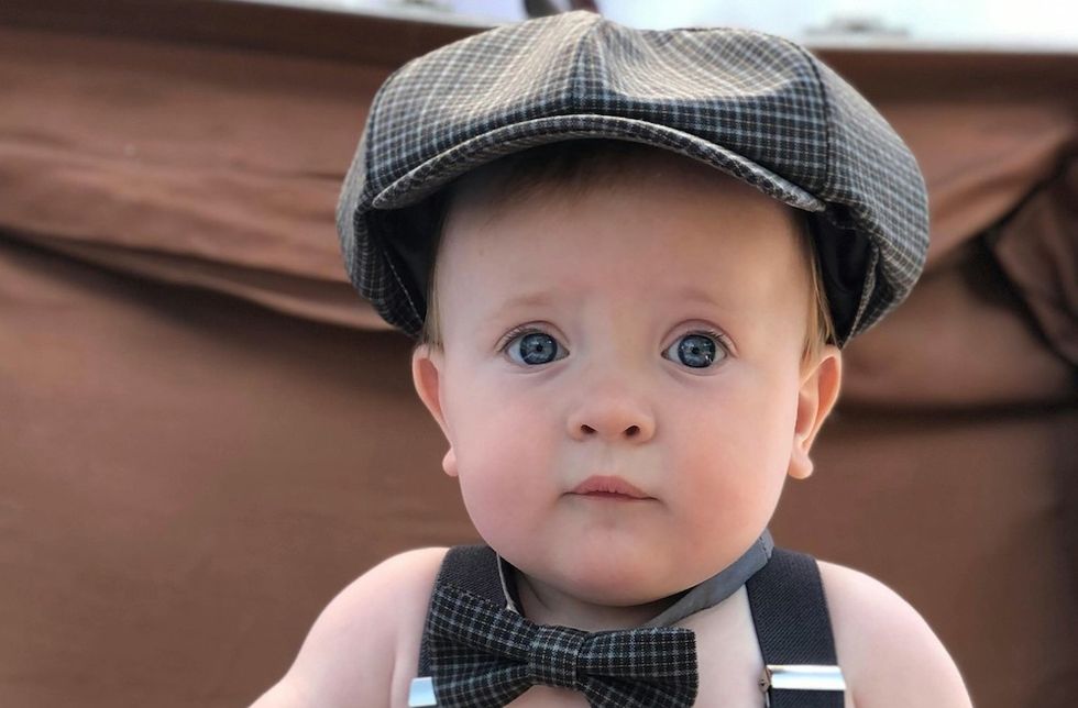 a baby boy with a news cap and a bowtie on