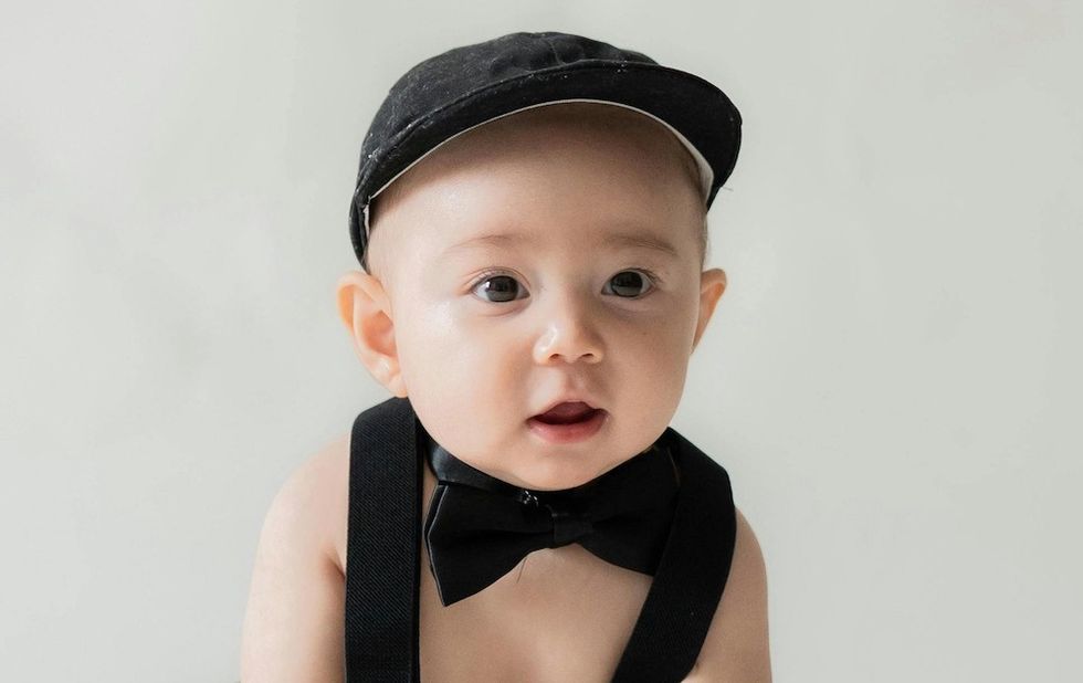 a baby boy with a news cap and a bowtie on