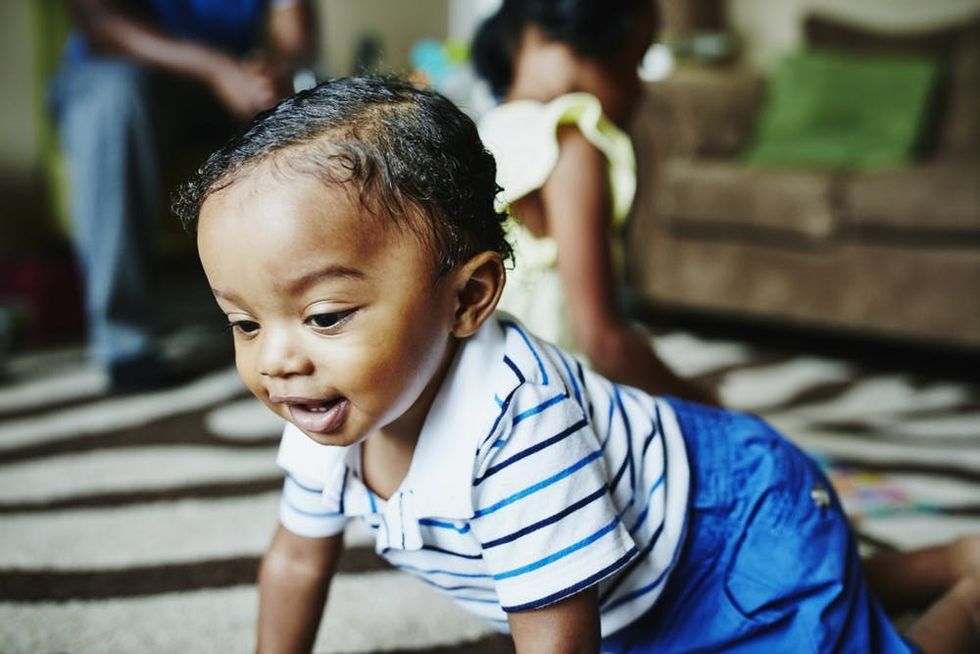 A baby crawls in his living room