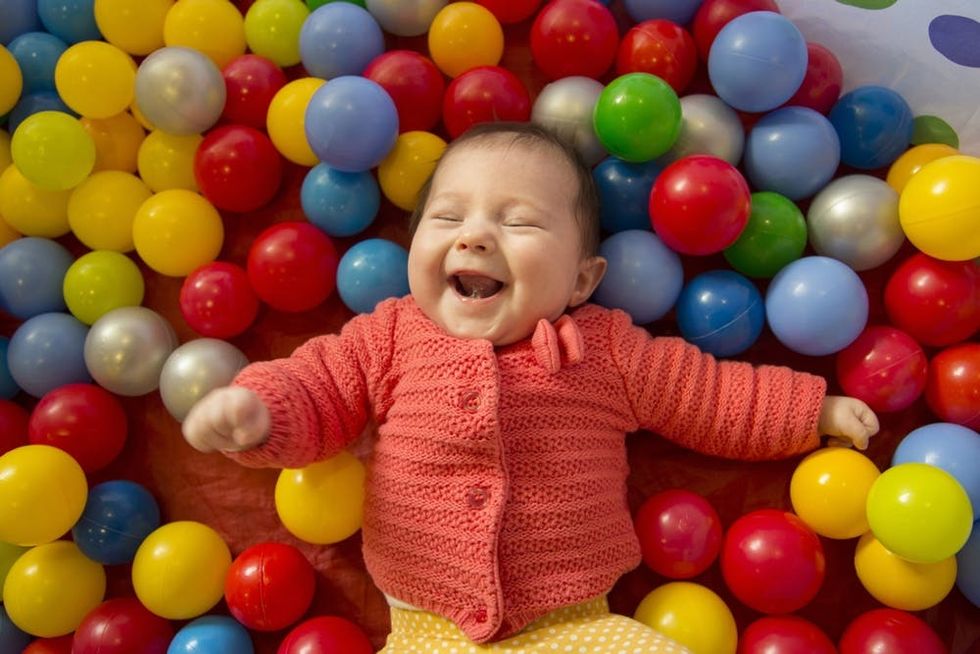 A baby laughs in a ball pit