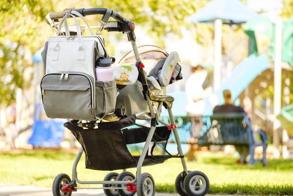 A baby stroller with a diaper bag at the park.