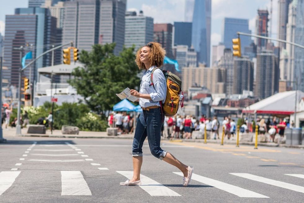 A backpacker crosses the street in a busy city