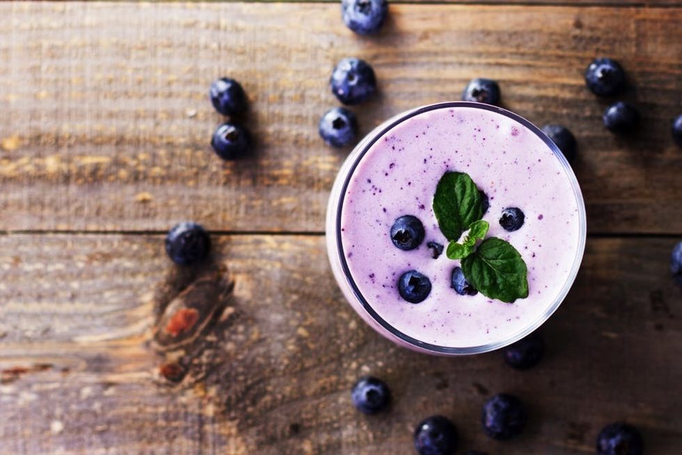 A blueberry yogurt smoothie rests on a wooden table