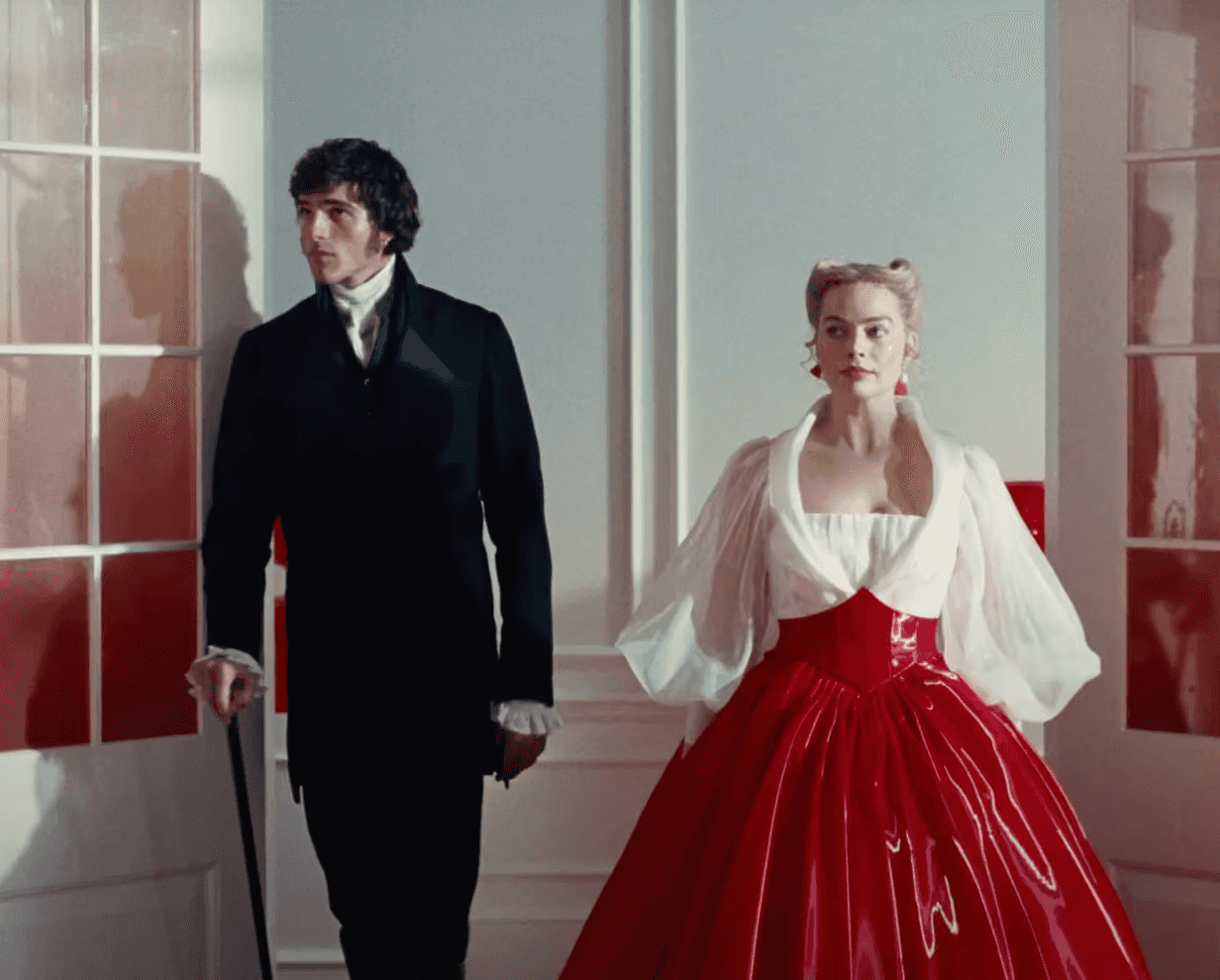 A couple in vintage attire pose in a brightly lit, elegant room with red accents.