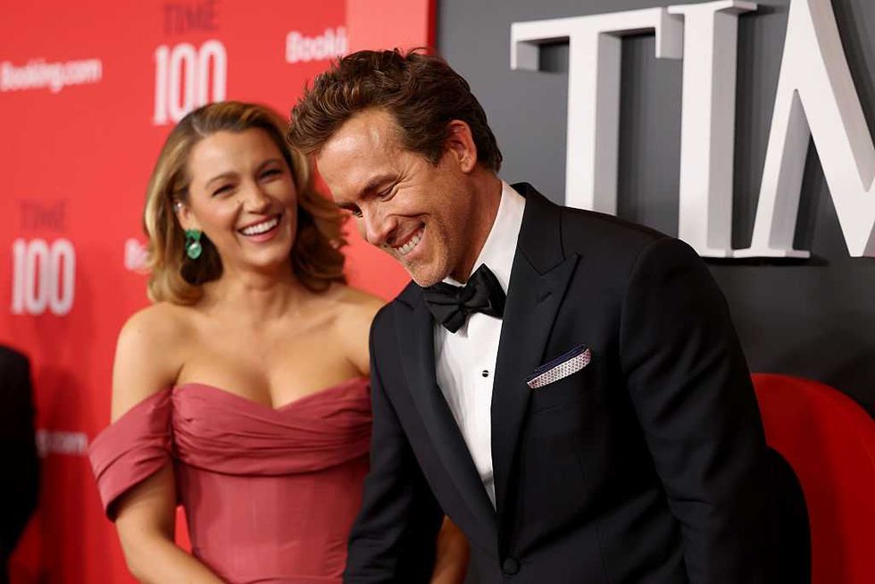 A couple laughing on the red carpet at a "Time 100" event.