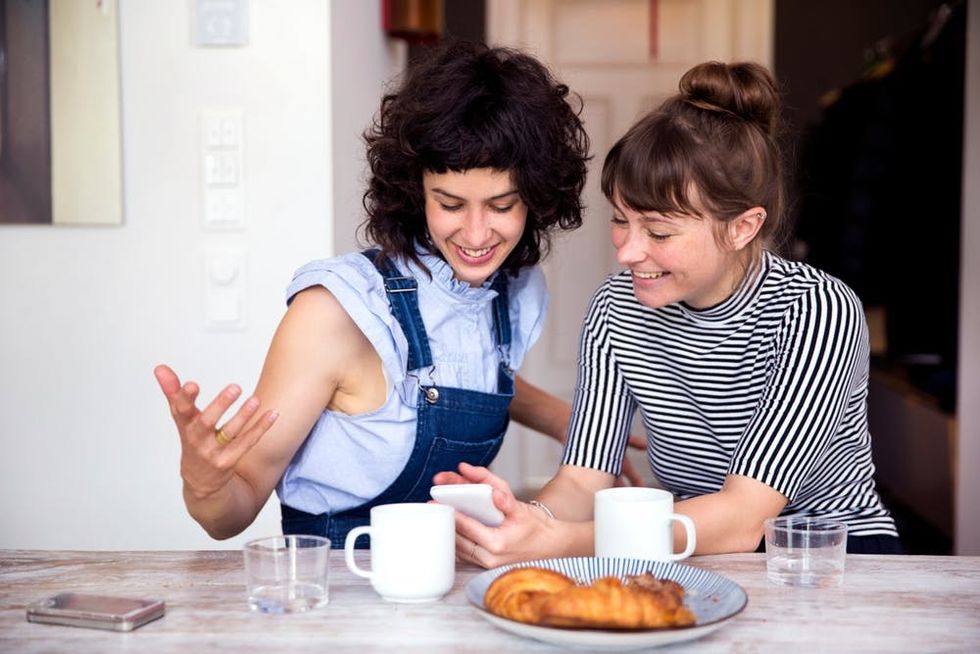 A couple looks at a phone screen while they eat breakfast