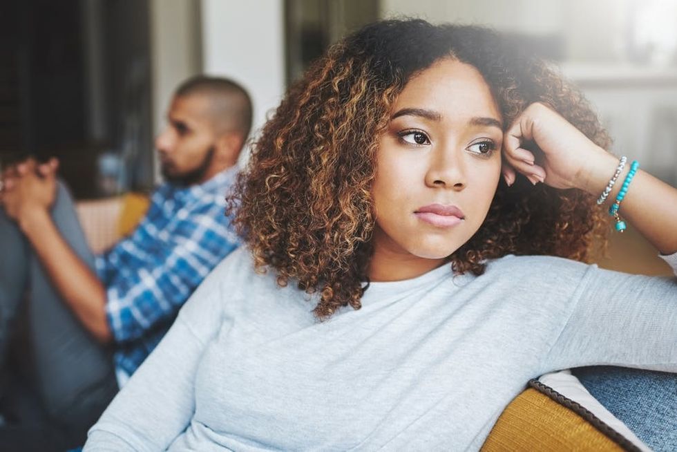 A couple sits tensely on a sofa