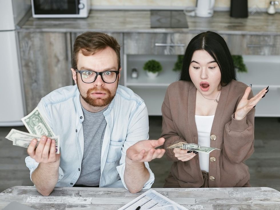 a couple sitting at a table gasping at money