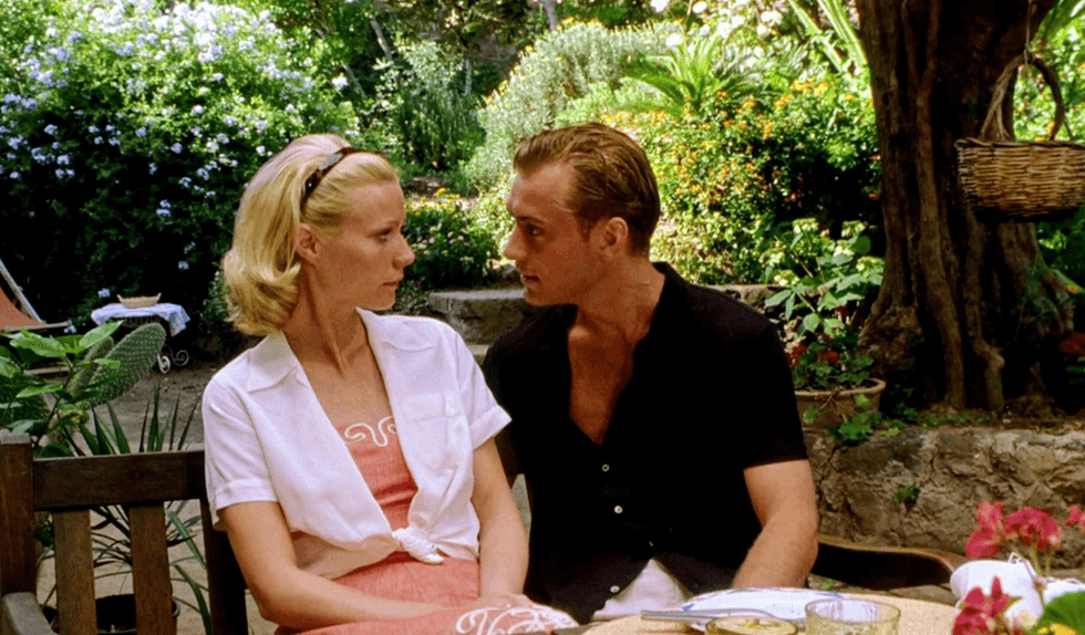 A couple sitting closely, talking in a lush garden setting.