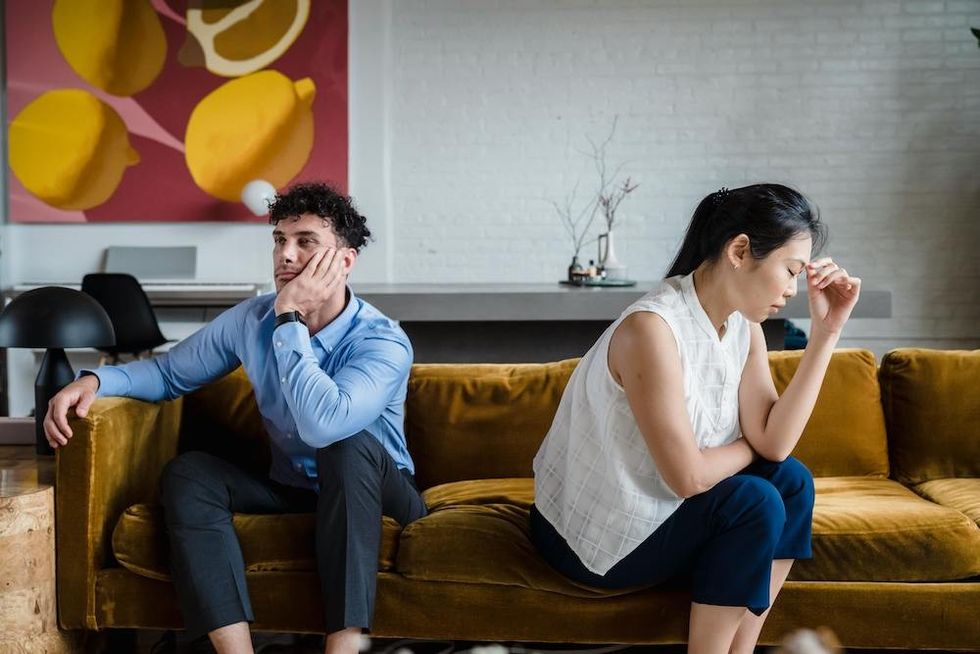 a couple sitting on the couch, facing away from each other