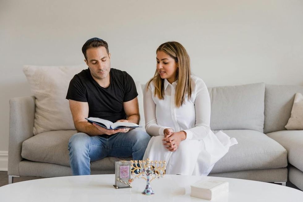 a couple sitting on the couch with a book