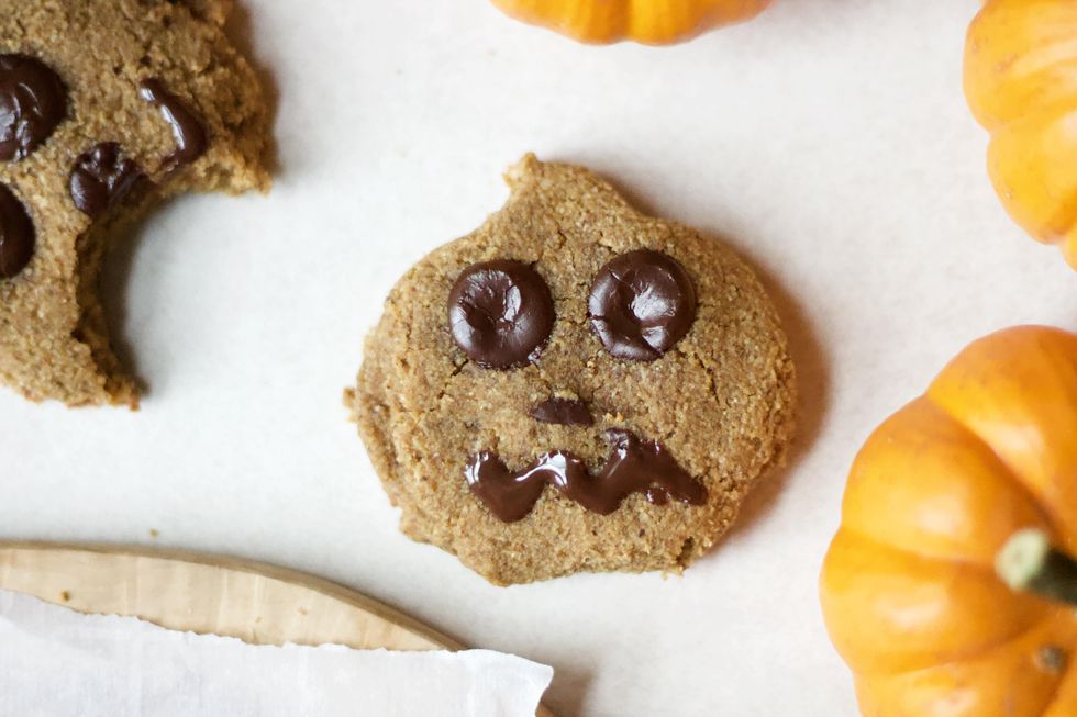 A decorated Paleo Halloween Pumpkin Cookie on a tray with small pumpkins