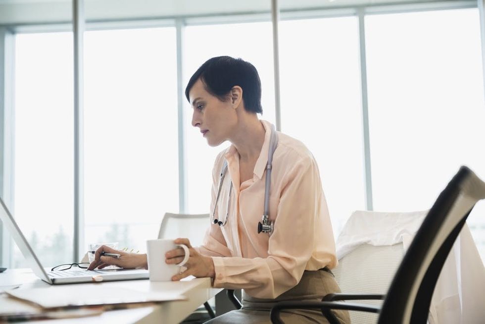 A doctor works on a laptop in her office
