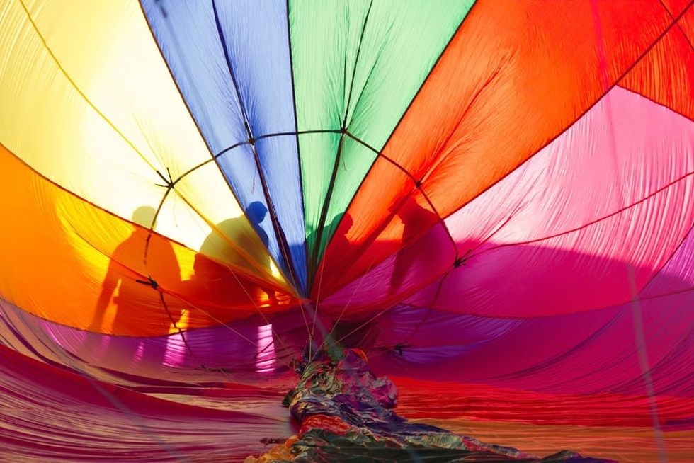 A flight crew inspects their hot air balloon as it inflates