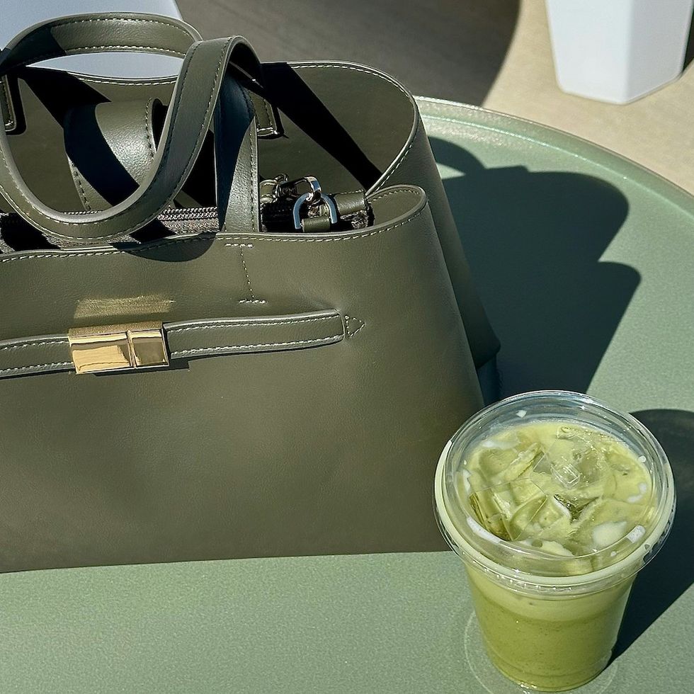 a green bag on a green table next to a cup of matcha