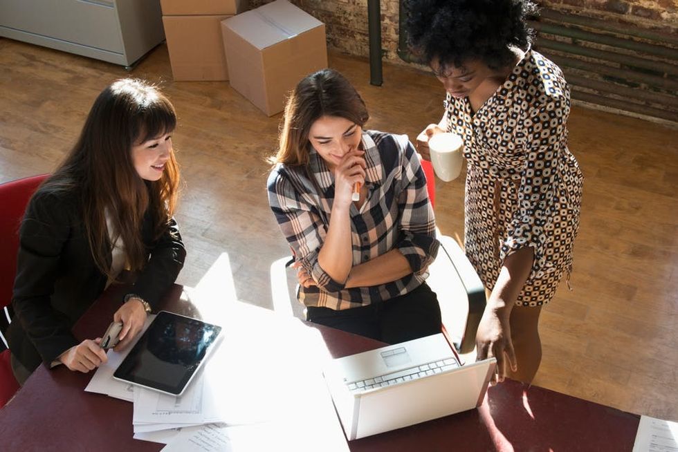 A group of coworkers share a laptop