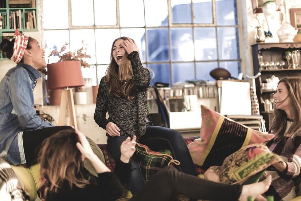 A group of friends laughs together in a living room