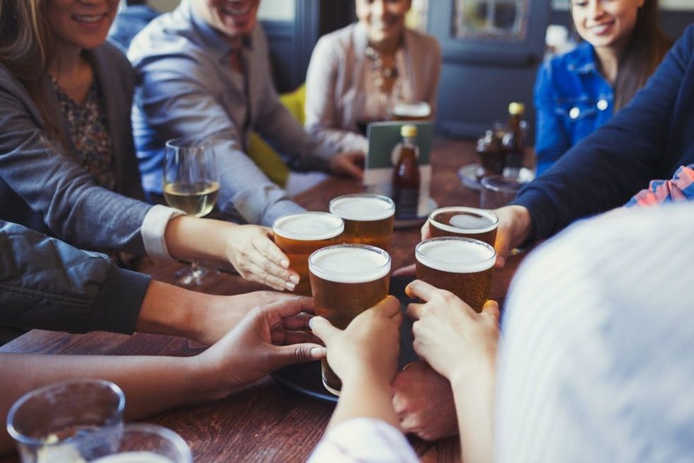 A group of friends reach for glasses of beer
