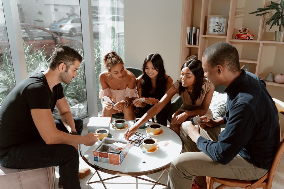 A group of friends sit around a table and play a board game.