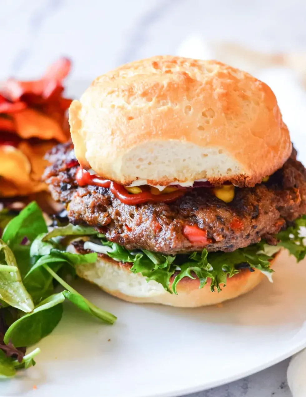 A hamburger is sitting on a white plate.
