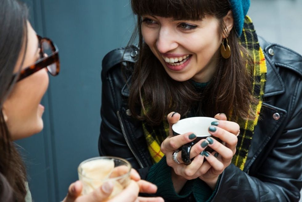 A laughing woman cradles a mug in her hands