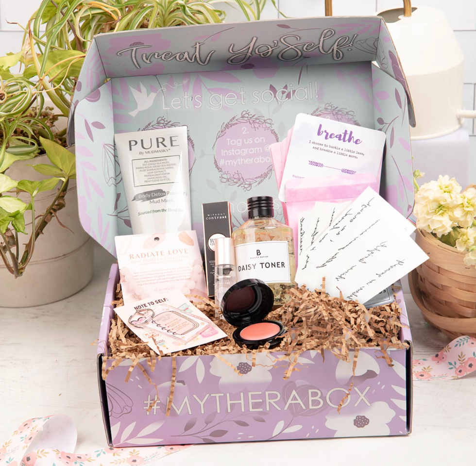 A lilac self-care box with skincare, cosmetics, and inspirational cards.