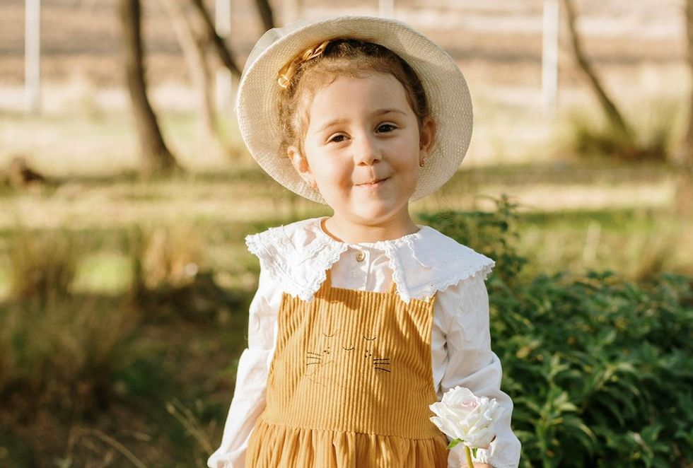 a little girl in a dress and a hat