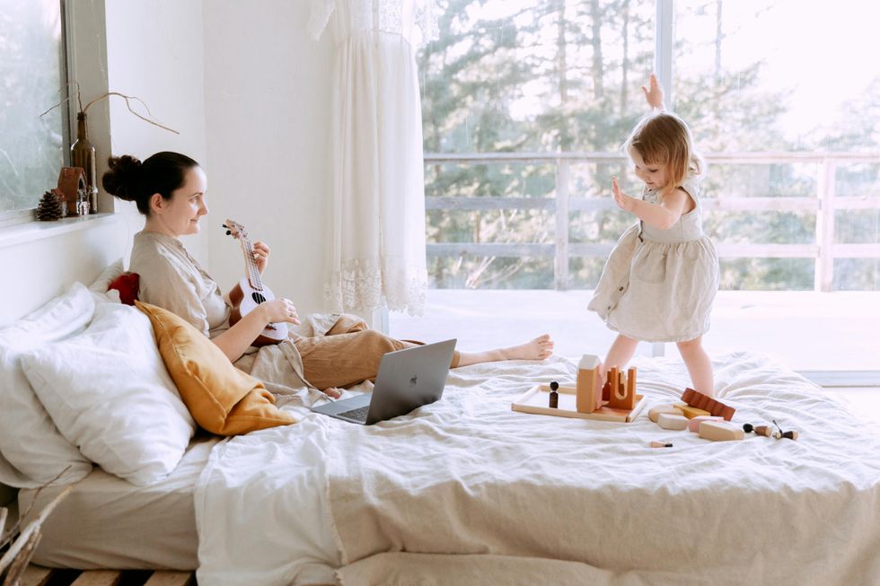 a little toddler playing in bed with her mom
