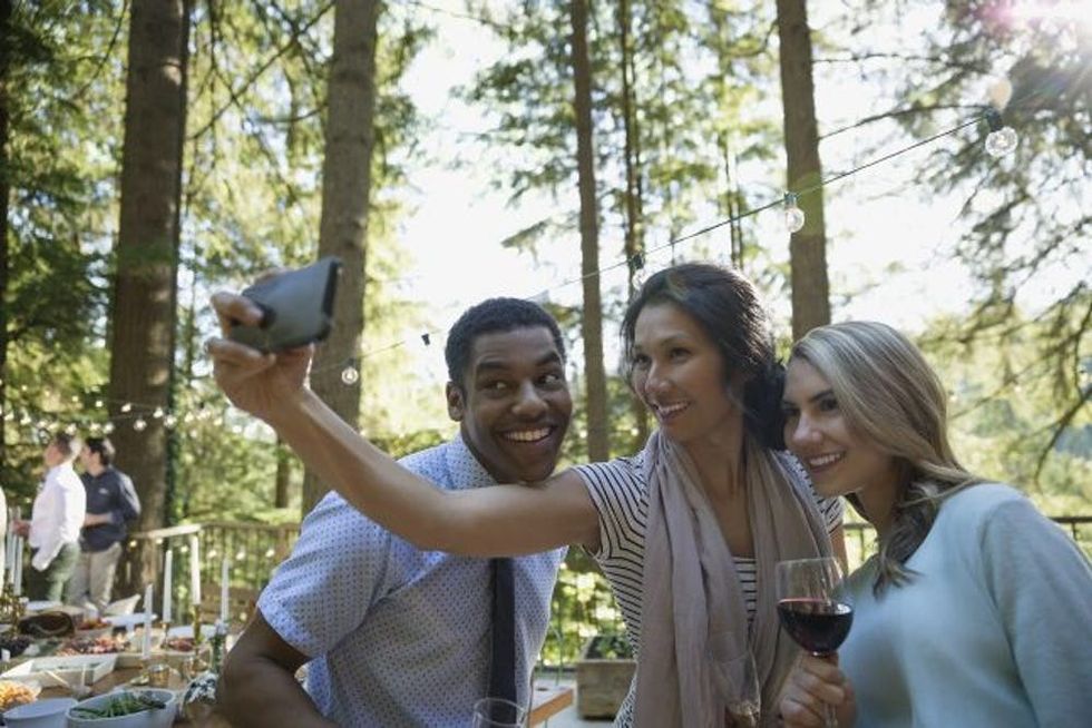 A man and two women take a selfie together at a wedding reception