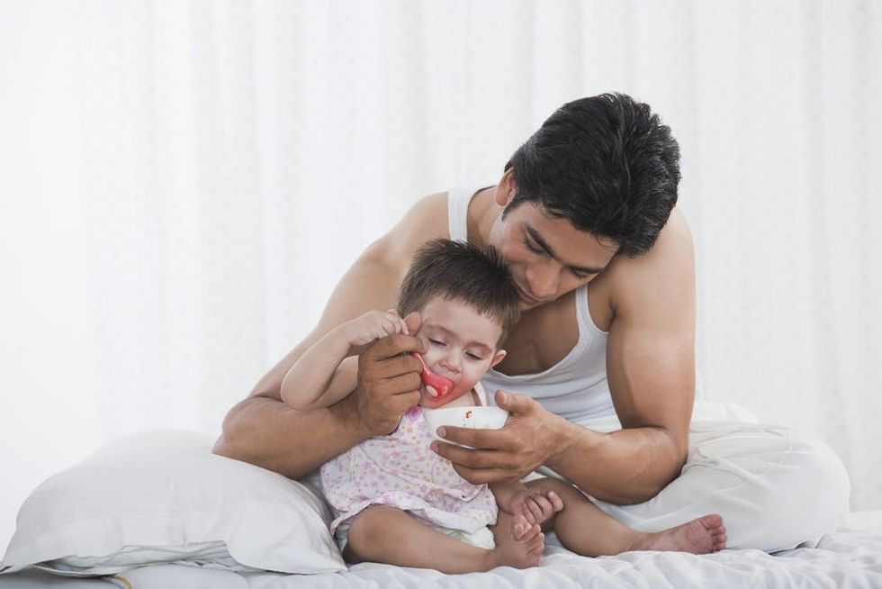 A man feeds porridge to his daughter
