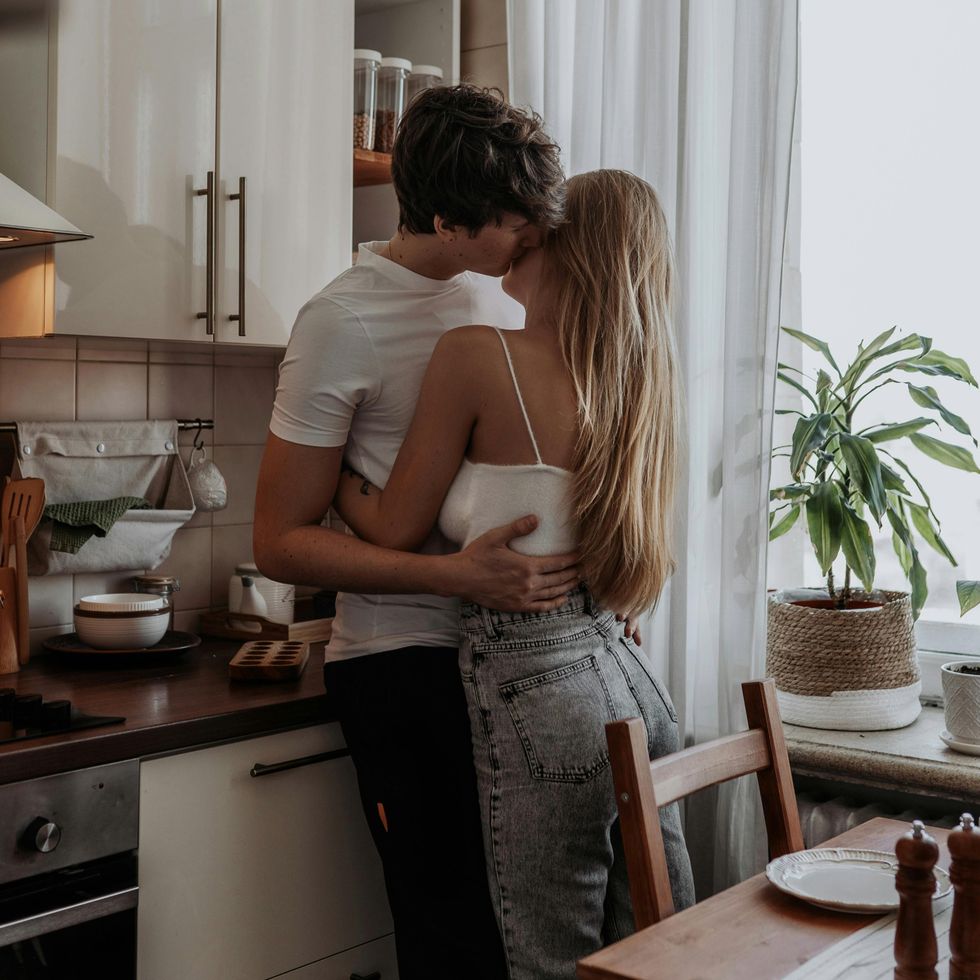 a man kissing his girlfriend on the cheek in the kitchen