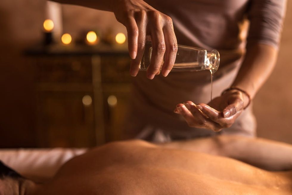 A massage therapist pours oil into their hand