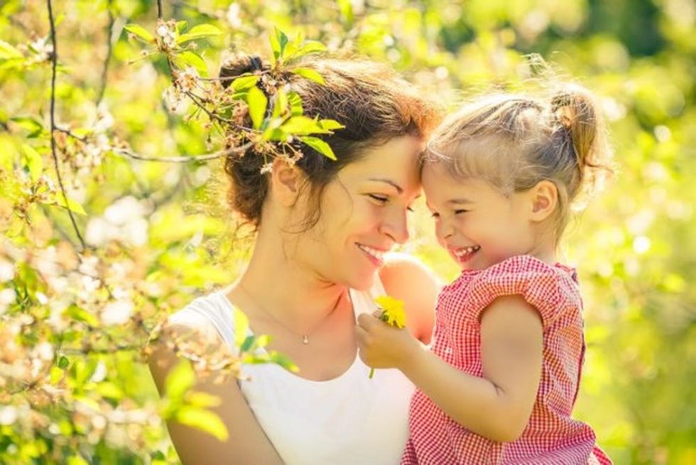 A mother and daughter laugh together in a park