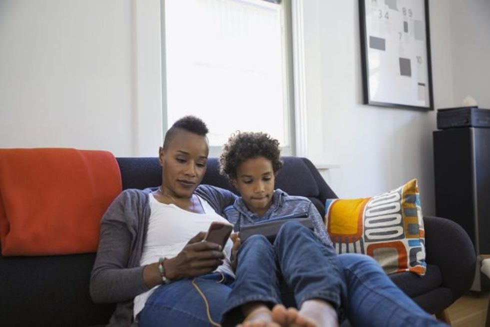 A mother and son sit together as they use different devices