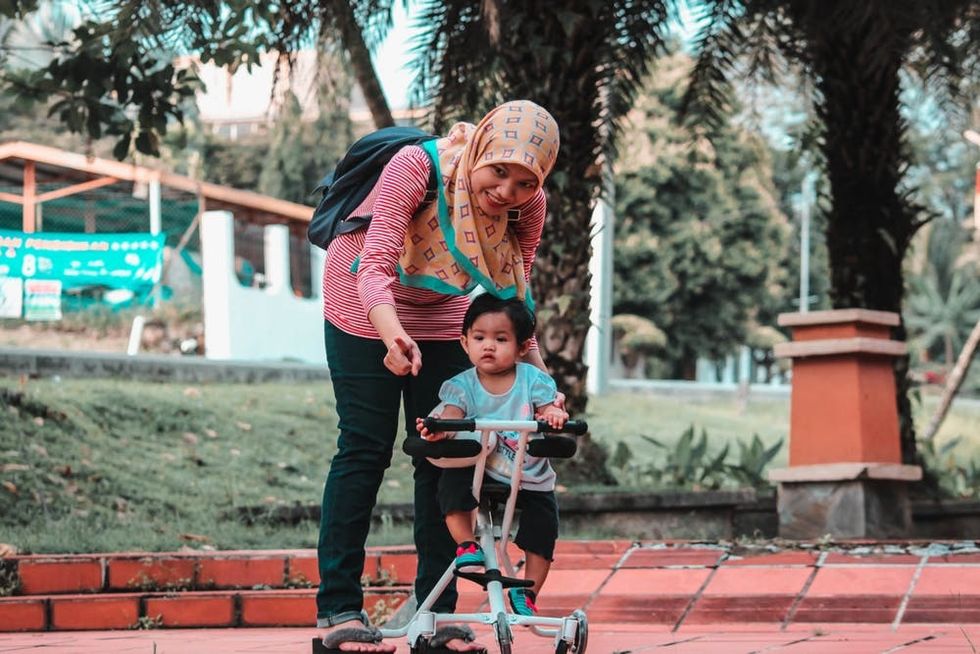 A mother encourages her child on a scooter