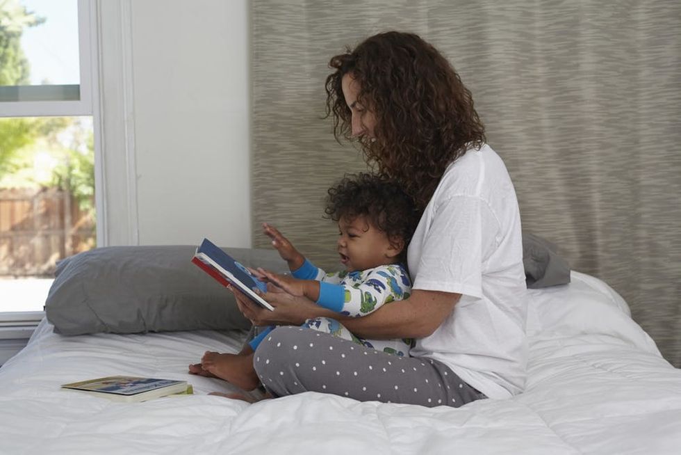 A mother reads to her toddler in bed