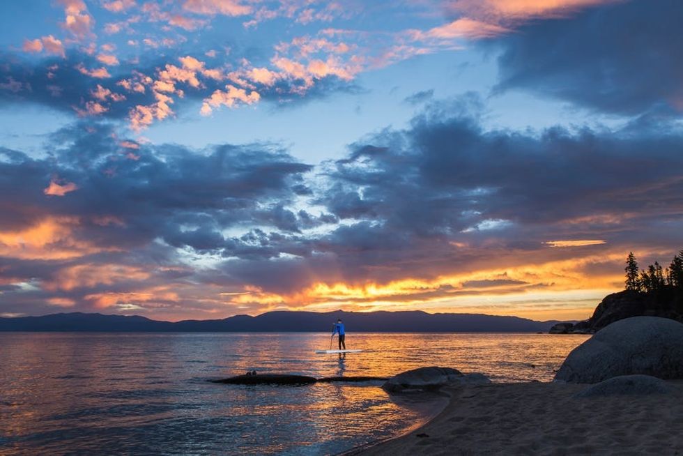 A paddleboarder crosses Lake Tahoe against a brilliant sunset
