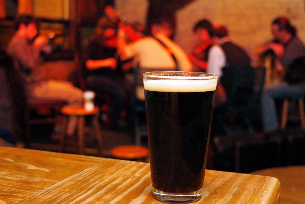 A pint of stout rests on a table in front of a group of Irish traditional musicians