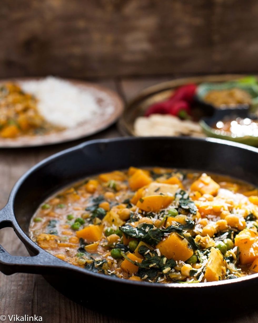 A pot of butternut squash curry is in a pot on a table.