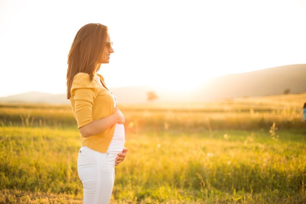 A pregnant woman enjoys the sun in a field