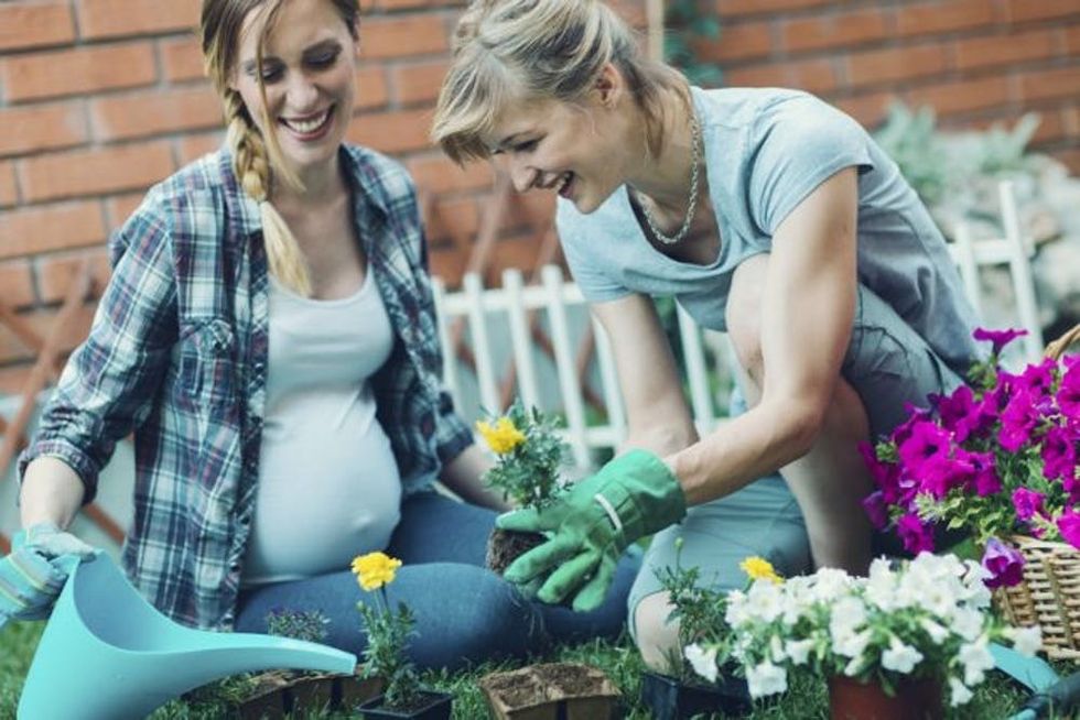 A pregnant woman gardens with her partner
