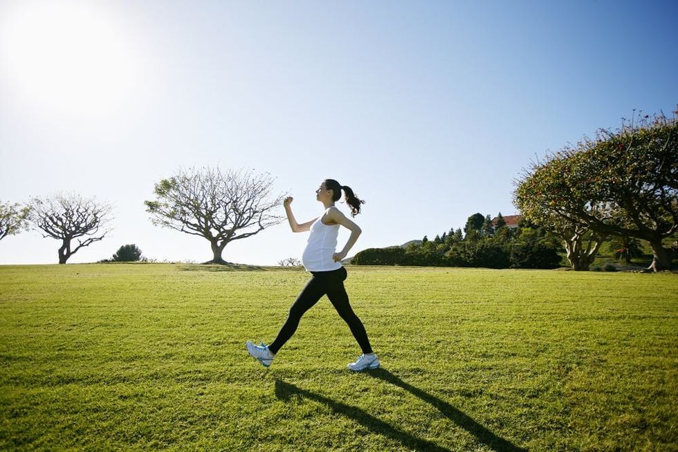 A pregnant woman walks energetically across a field