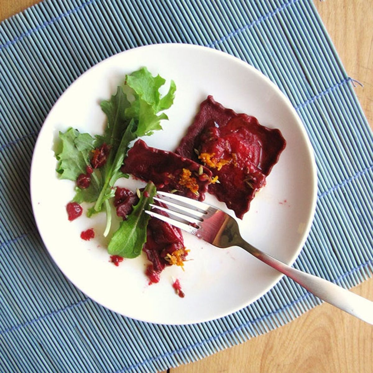 A round white plate with spinach and beet ravioli and fresh arugula is one of our favorite homemade pasta recipes.