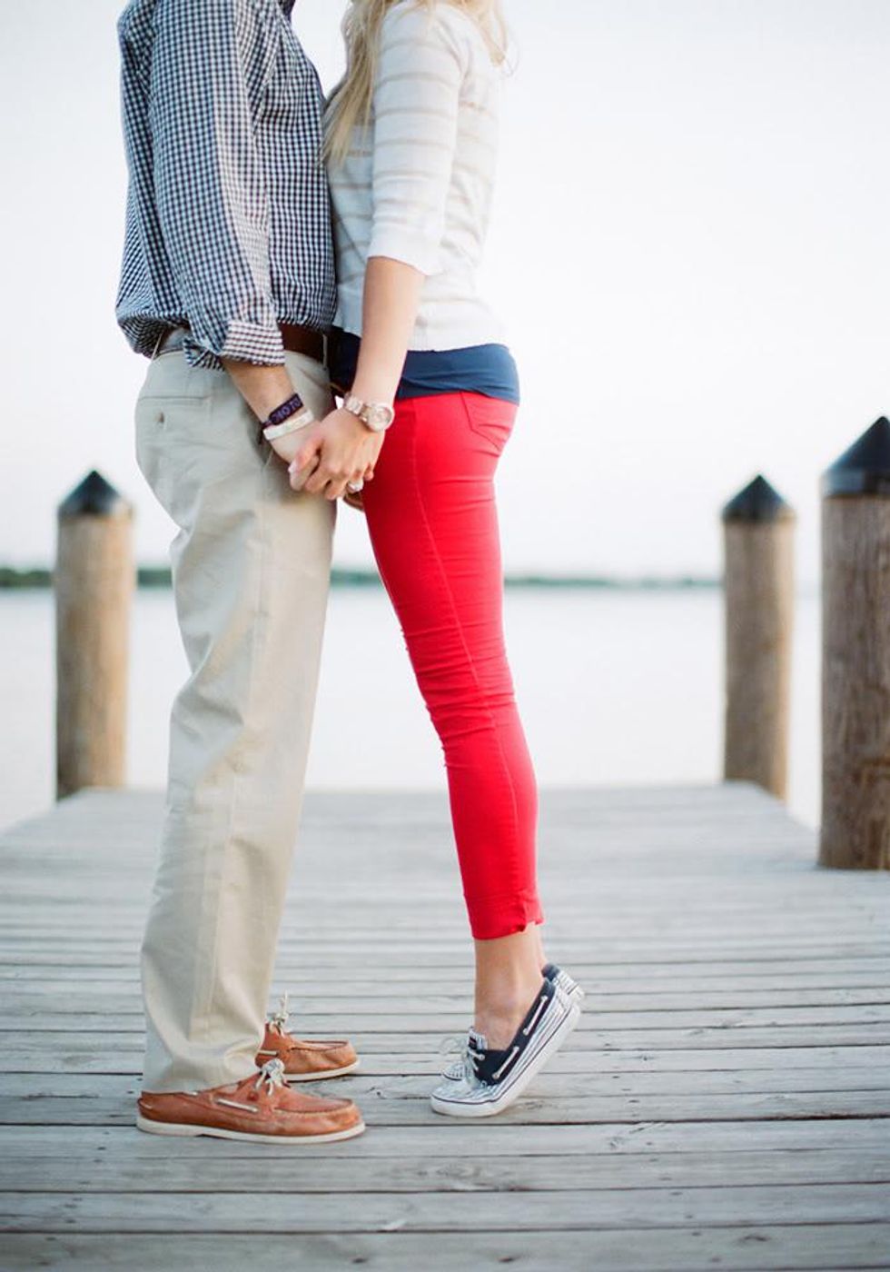 a shot of a couple's nautical-inspired pants and shoes while they kiss