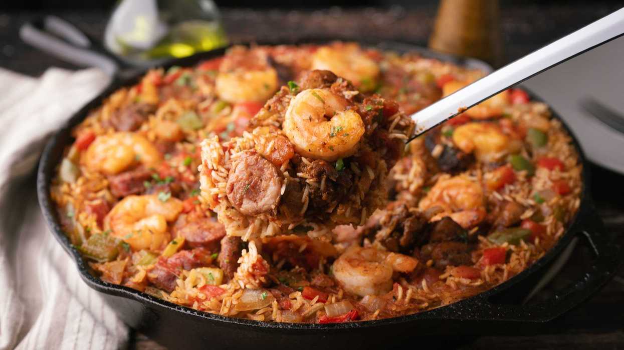 A skillet of jambalaya with shrimp, sausage, and vegetables, served with a ladle.