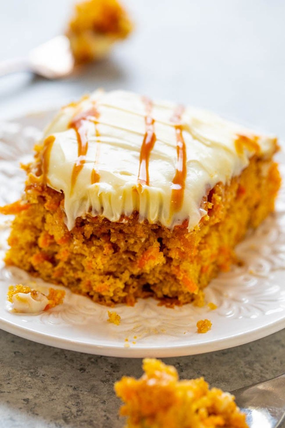 A slice of moist salted caramel carrot cake sits on top of a white plate.
