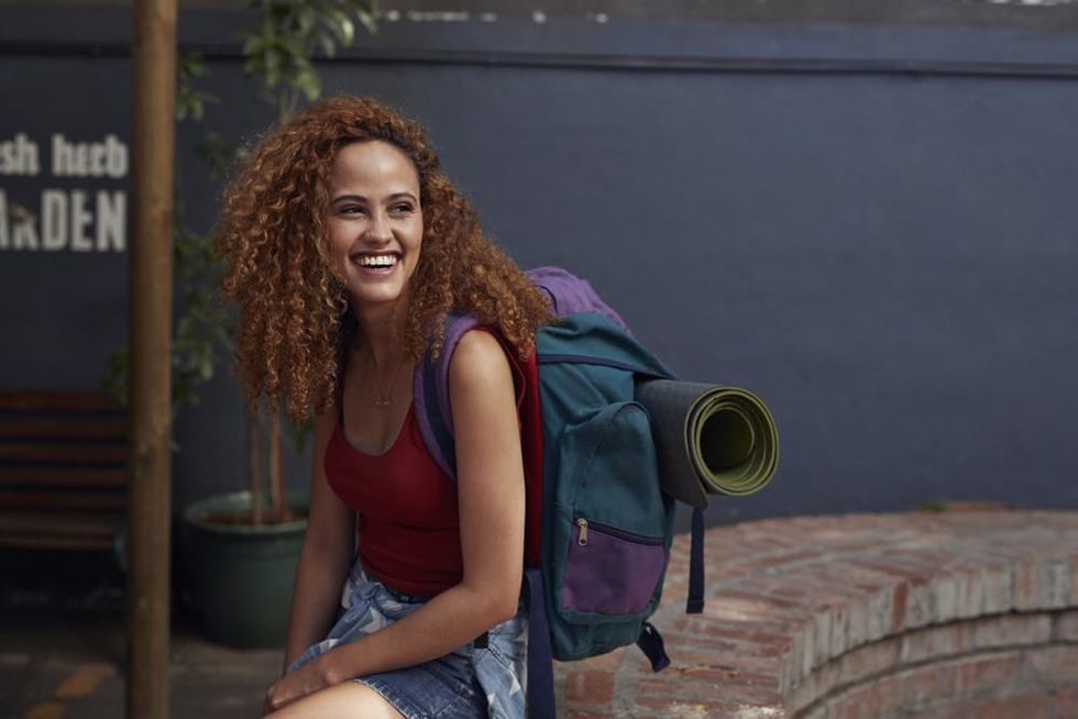 A smiling backpacker sits in the courtyard of a hostel