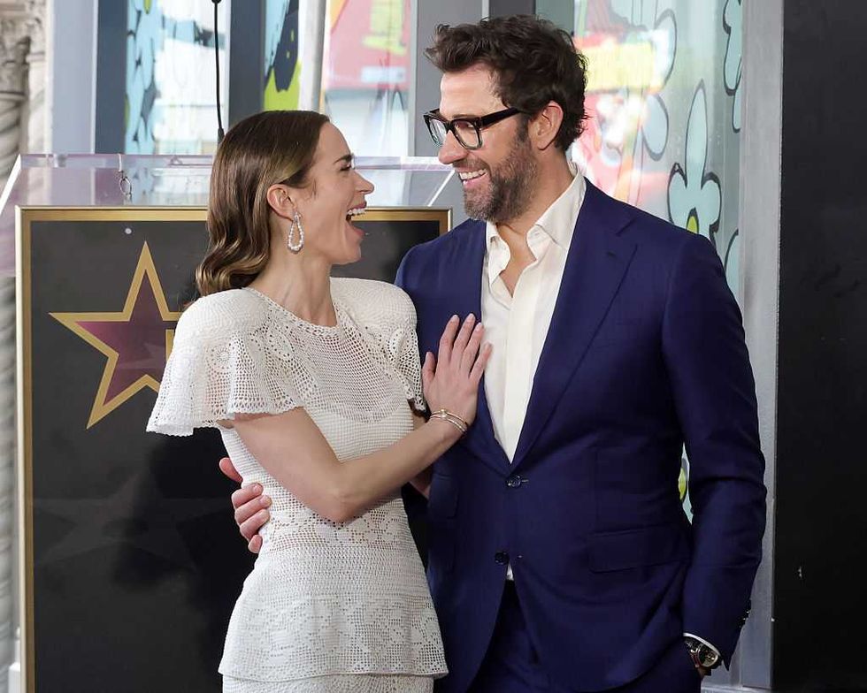 A smiling couple embraces, standing together near a star emblem.