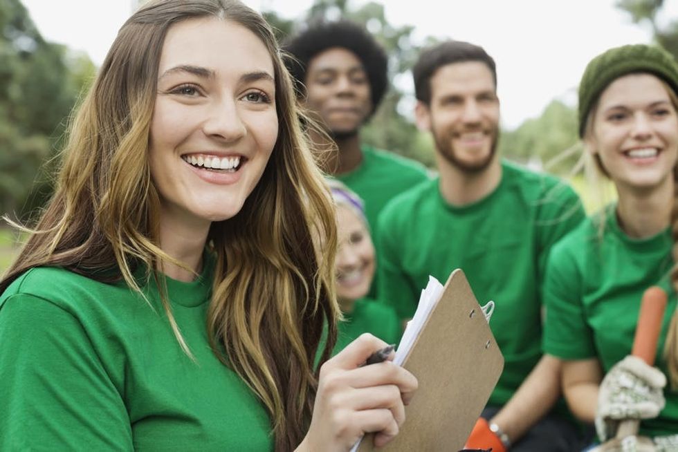 A smiling woman holds a clipboard in front of her team